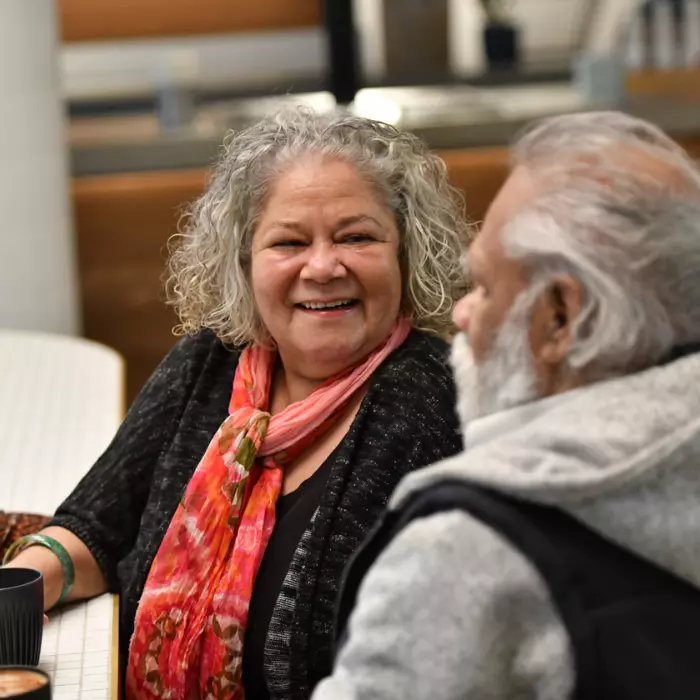 Two indigenous elderly friends smiling together over coffee