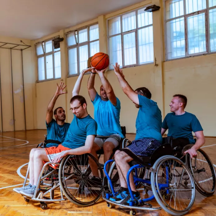 Group of disabled friends in wheelchairs playing basketball