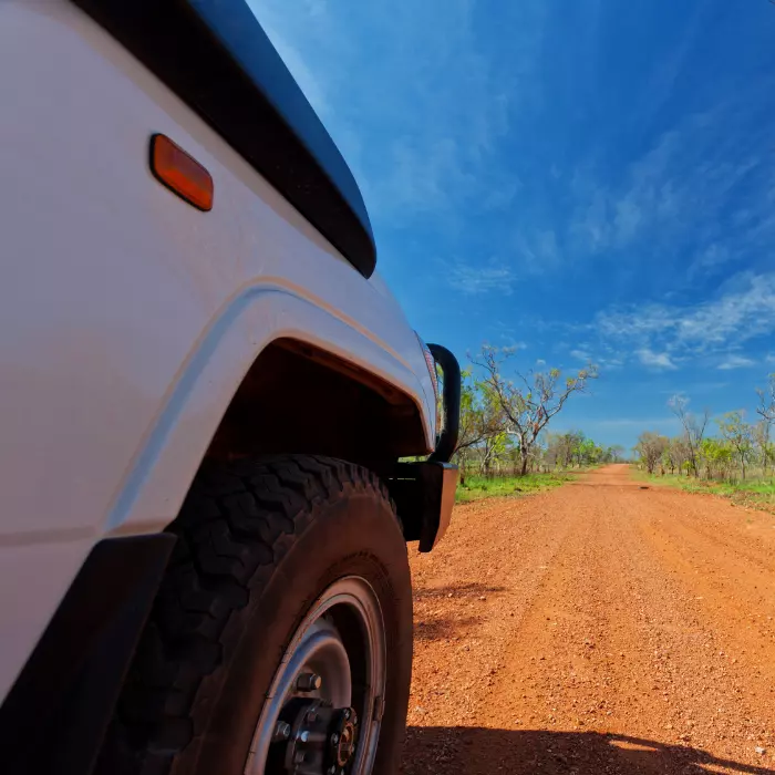 Close up of front of of car and wheel from back angle driving on red dirt in the Northern Territory