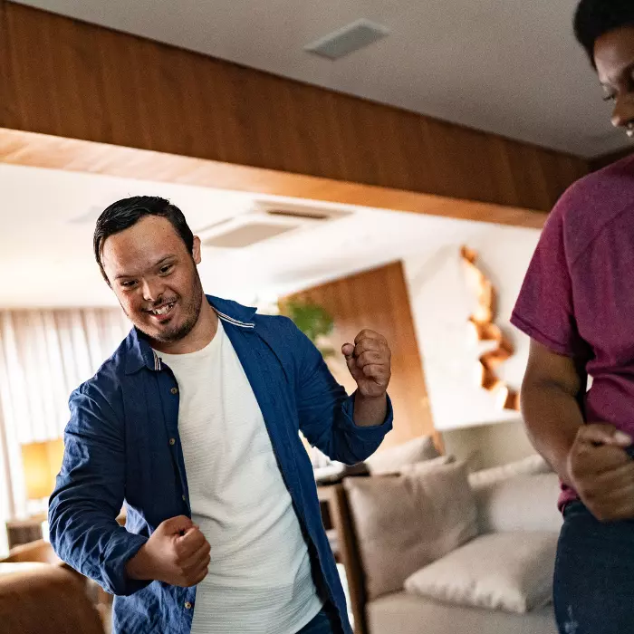 Man with down syndrome dancing in living room with friend