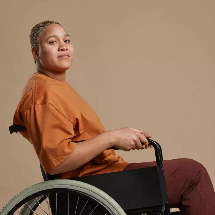 Disabled woman in wheelchair smiling softly at the camera